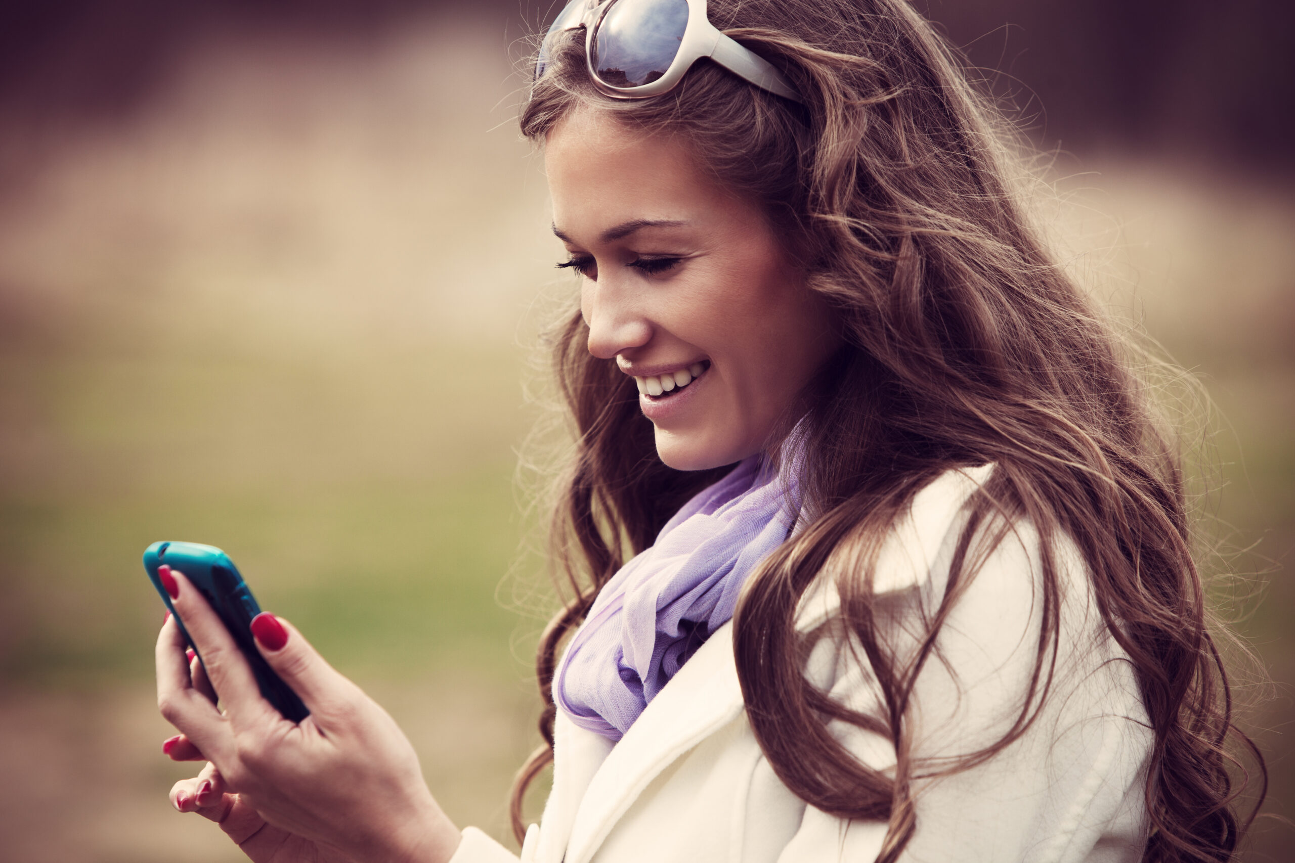 smiling young woman reading message on her smartphone outdoor shot